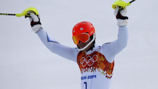 Ein Skirennläufer mit rotem Helm und Skibrille jubelt mit erhobenen Armen.