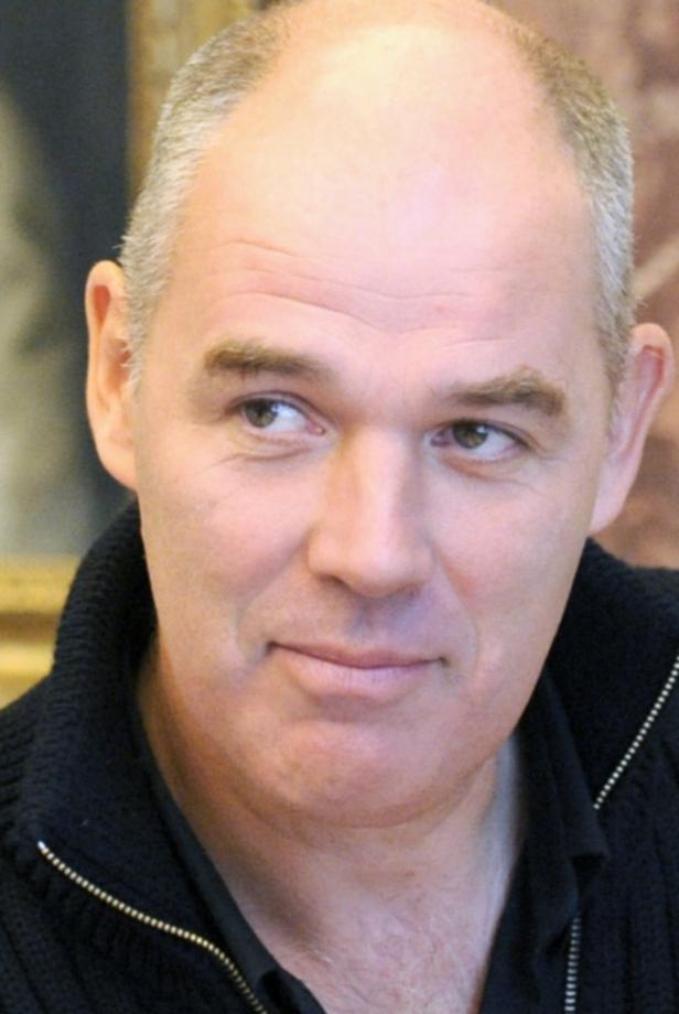 Porträt eines Mannes mit kurzen, grauen Haaren und einem schwarzen Pullover.