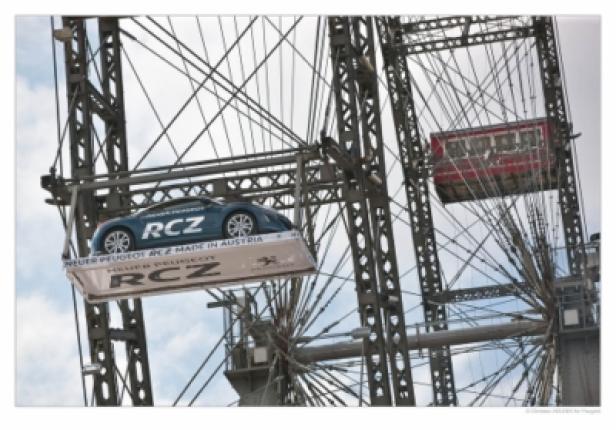 Ein blauer Peugeot RCZ auf einem Waggon des Wiener Riesenrads.
