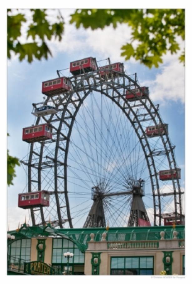 Das Wiener Riesenrad im Prater mit seinen roten Waggons vor blauem Himmel.