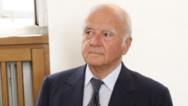 Ein älterer Mann in Anzug und Krawatte blickt zur Seite.