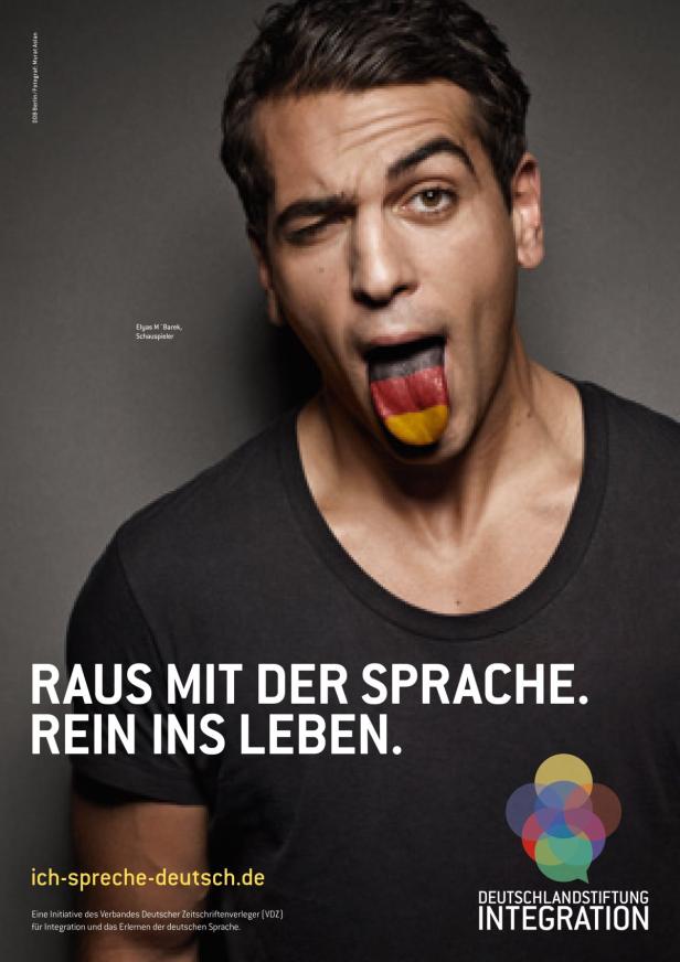 Der Schauspieler Elyas M'Barek zwinkert und zeigt seine Zunge in den deutschen Nationalfarben.