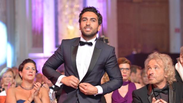 Ein Mann im Smoking schließt seinen Jackettknopf vor Publikum, darunter Thomas Gottschalk.