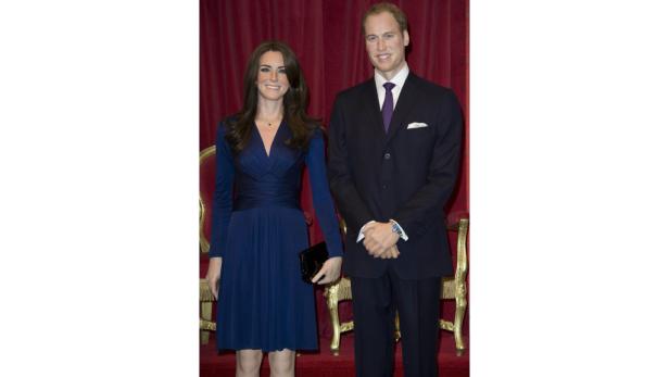 Prinz William und Kate Middleton posieren vor einem roten Vorhang.