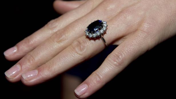 Ein blauer Saphirring, umgeben von Diamanten, an der Hand einer Frau.