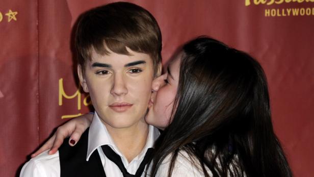 Eine Frau gibt der Wachsfigur von Justin Bieber einen Kuss auf die Wange.