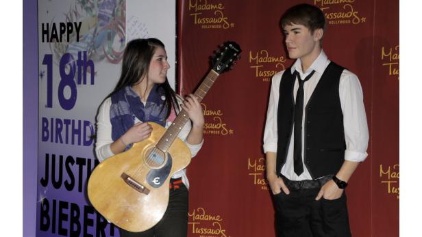 Eine junge Frau posiert mit einer Gitarre neben der Wachsfigur von Justin Bieber bei Madame Tussauds.