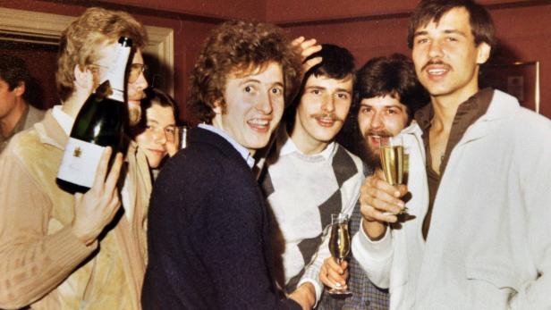 Eine Gruppe junger Männer feiert mit Champagner.