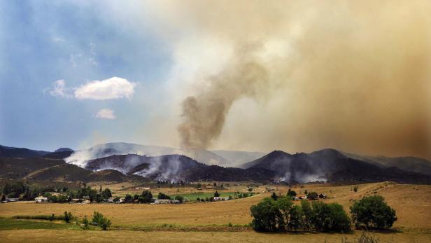 Ein Waldbrand wütet in den Bergen in der Nähe einer kleinen Ortschaft.