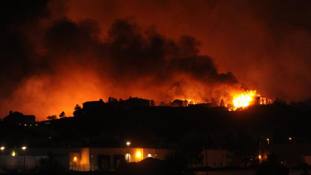 Ein Haus steht in Flammen, Rauch steigt in den Nachthimmel.