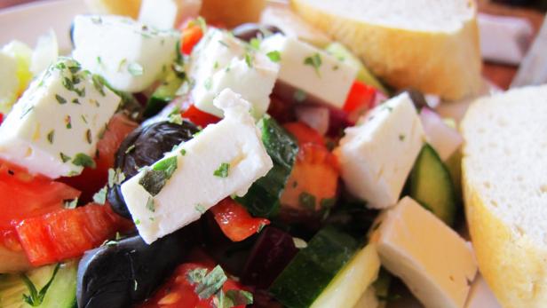 Ein griechischer Salat mit Feta, Oliven, Tomaten, Gurken und Brot.
