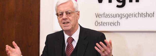 Ein Mann mit Brille gestikuliert vor dem Schriftzug „Verfassungsgerichtshof Österreich“.