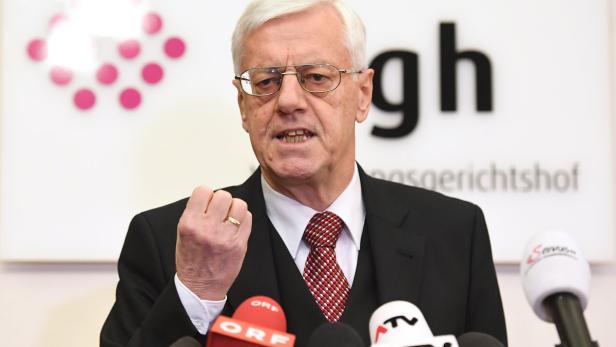 Ein älterer Mann mit Brille gestikuliert vor Mikrofonen des ORF und anderer Sender.