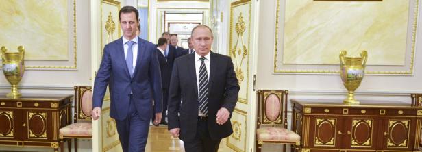 Wladimir Putin und Baschar al-Assad gehen durch einen prunkvollen Korridor.