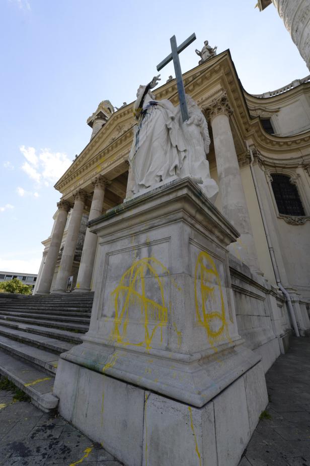 Eine Statue vor einer Kirche ist mit gelber Farbe beschmiert.