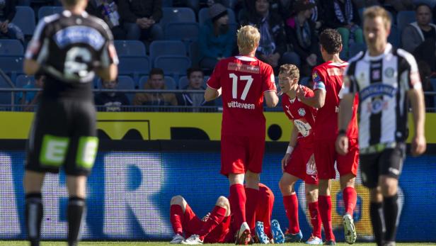 Fußballspieler in roten Trikots nach einem Spiel auf dem Rasen.