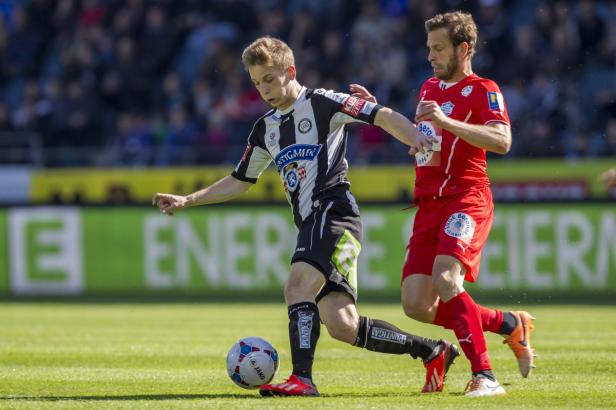 Zwei Fußballspieler kämpfen um den Ball auf dem Spielfeld.