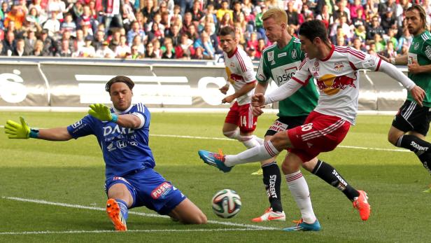 Ein Fußballspieler schießt den Ball, während der Torwart versucht, ihn abzuwehren.