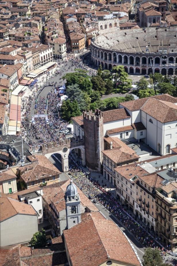 Luftaufnahme von Verona, Italien, mit Menschenmassen, die durch die Stadt zum Amphitheater laufen.