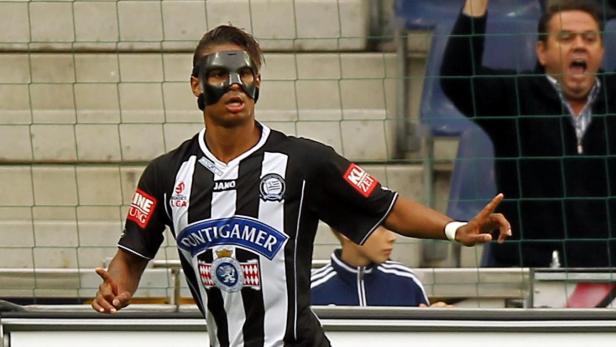 Ein Fußballspieler mit einer schwarzen Gesichtsmaske auf dem Spielfeld.