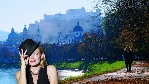 Eine Frau mit Hut vor der Kulisse von Salzburg mit Festung und Dom.