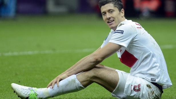 Robert Lewandowski sitzt auf dem Rasen und lächelt.