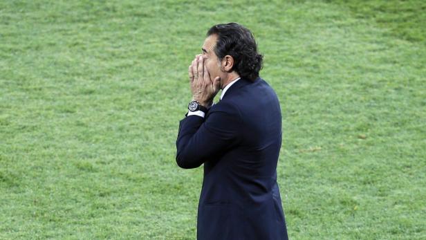 Ein Mann im Anzug steht auf einem Rasen und hält die Hände vor das Gesicht.