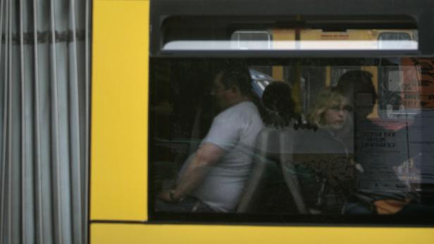 Menschen sitzen in einer gelben Straßenbahn.