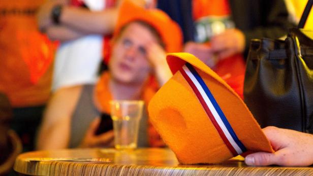 Ein orangefarbener Hut mit den Farben der niederländischen Flagge liegt auf einem Tisch.