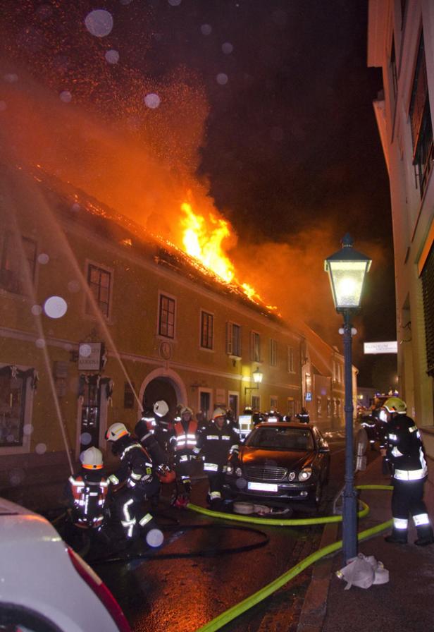 Ein Gebäude steht in Flammen, während Feuerwehrleute versuchen, das Feuer zu löschen.
