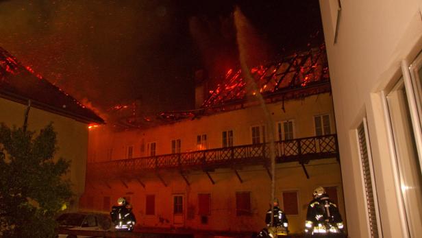 Feuerwehrleute bekämpfen einen Dachstuhlbrand in einem mehrstöckigen Gebäude.