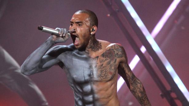Chris Brown tritt mit Farbe auf seinem Körper auf und singt in ein Mikrofon.