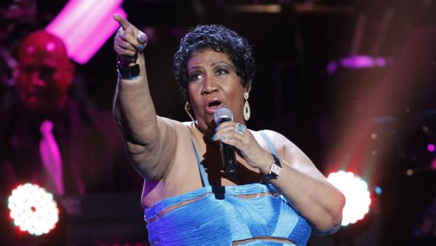 Aretha Franklin singt mit erhobenem Zeigefinger in ein Mikrofon.