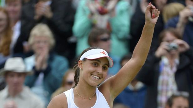 Eine Tennisspielerin jubelt mit erhobenem Arm vor einer Zuschauermenge.