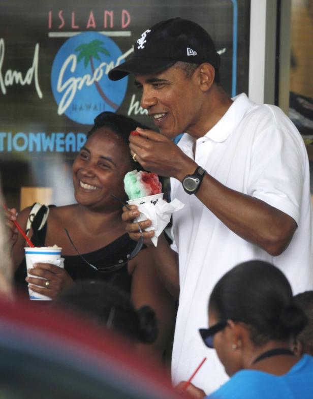 Barack Obama isst mit einer Frau ein Schabeis vor einem Laden auf Hawaii.
