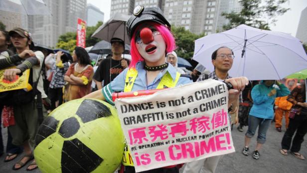 Eine als Polizistin verkleidete Person mit Clownsnase demonstriert gegen Atomkraft.