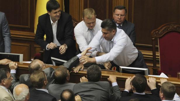 Mehrere Männer streiten sich während einer Sitzung in einem Parlament.