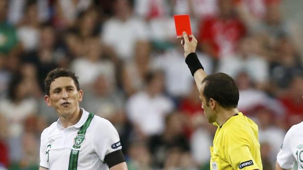 Ein Schiedsrichter zeigt einem Fußballspieler die Rote Karte.