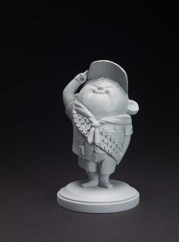 Eine graue Statue von Russell aus dem Film „Oben“, der im Pfadfinder-Outfit salutiert.