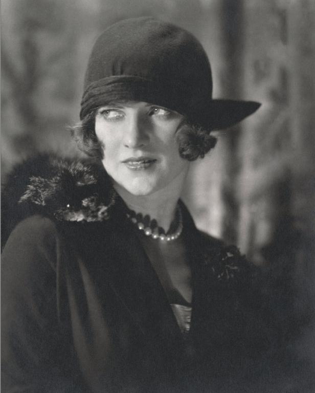 Eine Frau mit Hut und Perlenkette in einem Porträt der 1920er Jahre.