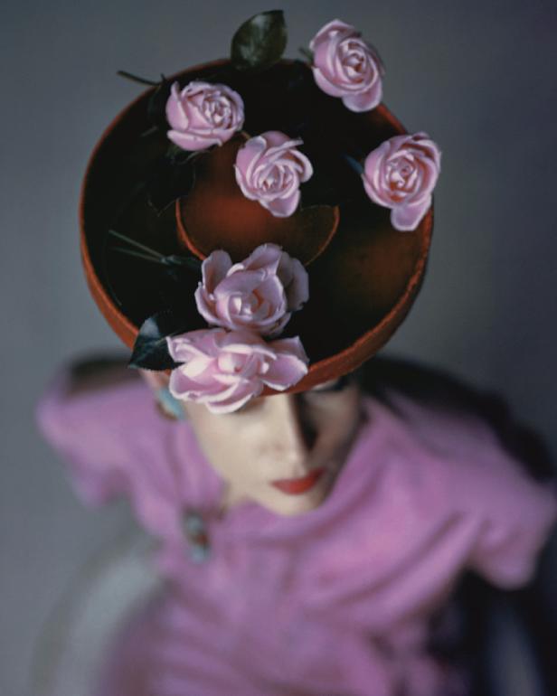 Eine Frau trägt einen Hut mit rosa Rosen und passendem Kleid.