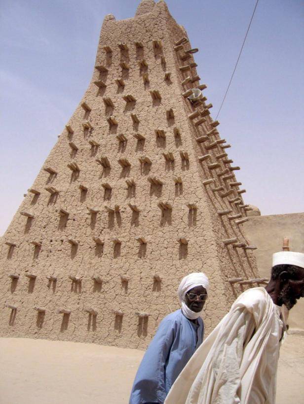 Die Große Moschee von Agadez, ein Lehmbauwerk, mit zwei Männern im Vordergrund.