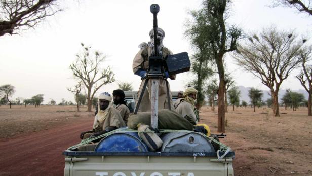 Bewaffnete Männer fahren auf der Ladefläche eines Toyota-Pickups durch eine trockene Landschaft.