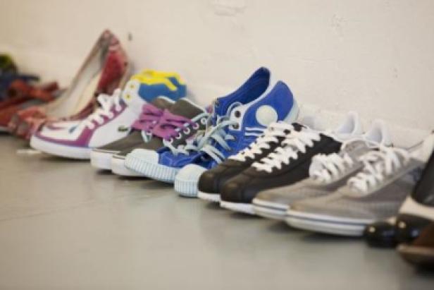 Eine Reihe verschiedener Schuhe stehen an einer Wand.