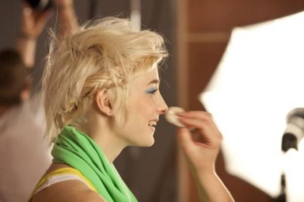 Eine Frau mit blonden Haaren wird geschminkt.