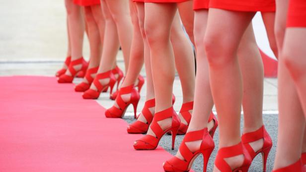 Eine Reihe von Frauen in roten Kleidern und roten High Heels auf einem roten Teppich.