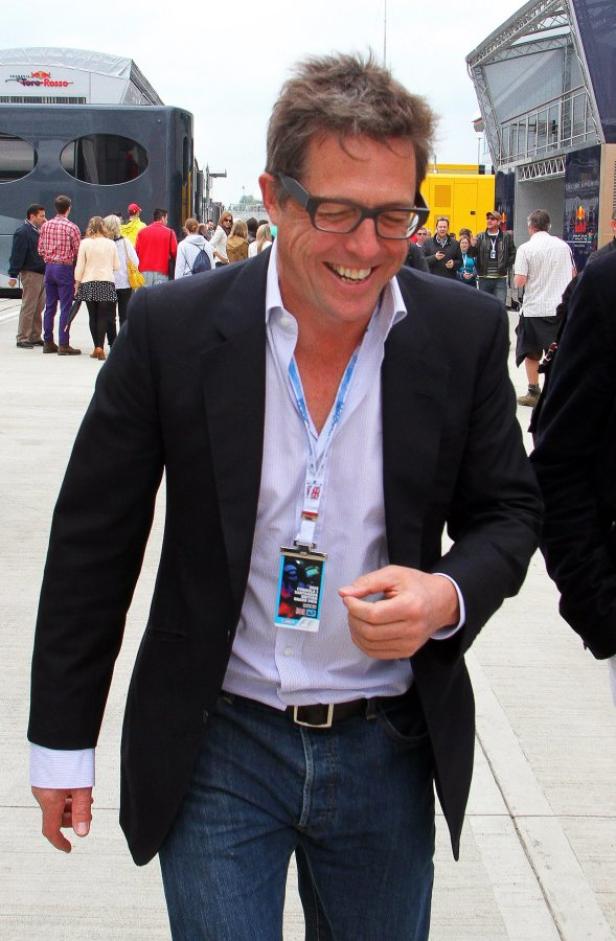 Hugh Grant lächelt bei einer Motorsportveranstaltung.