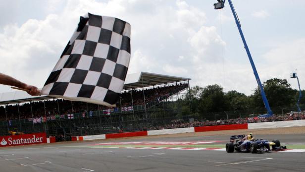 Ein Formel-1-Rennwagen überquert die Ziellinie unter einer schwarz-weiß karierten Flagge.