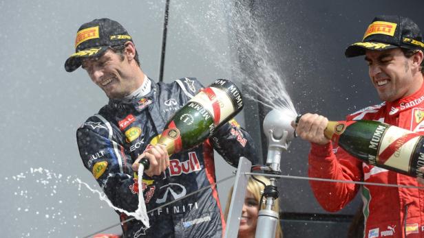Zwei Formel-1-Fahrer feiern mit Champagner auf dem Siegerpodest.