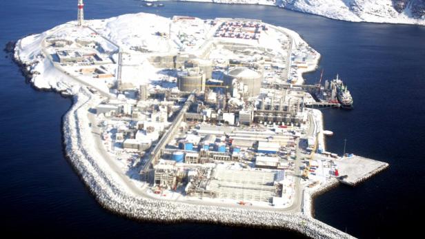 Luftaufnahme einer schneebedeckten Industrieanlage auf einer Insel im Meer.